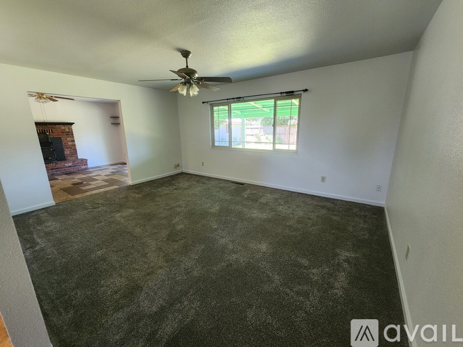 A room with a ceiling fan and a window with blinds.