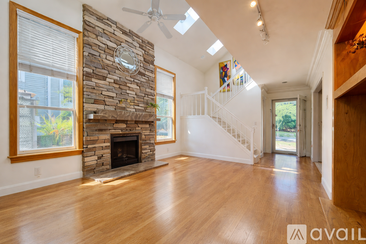 A spacious living room with wooden floors and a stone fireplace.