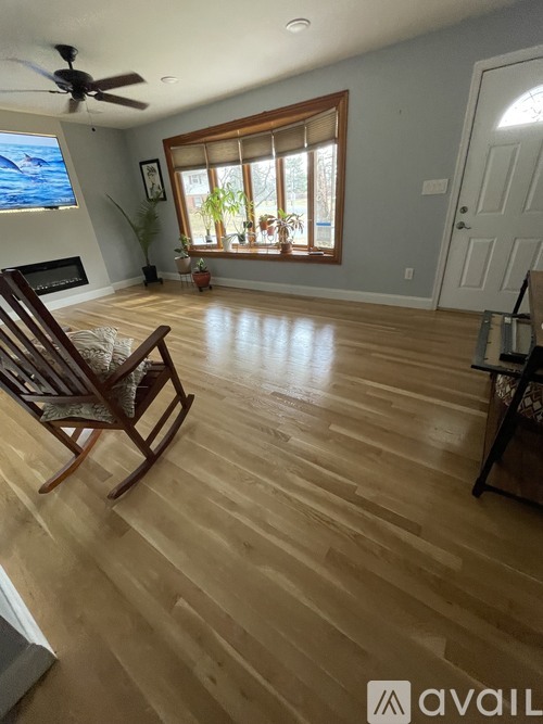 A room with wooden flooring and a rocking chair.