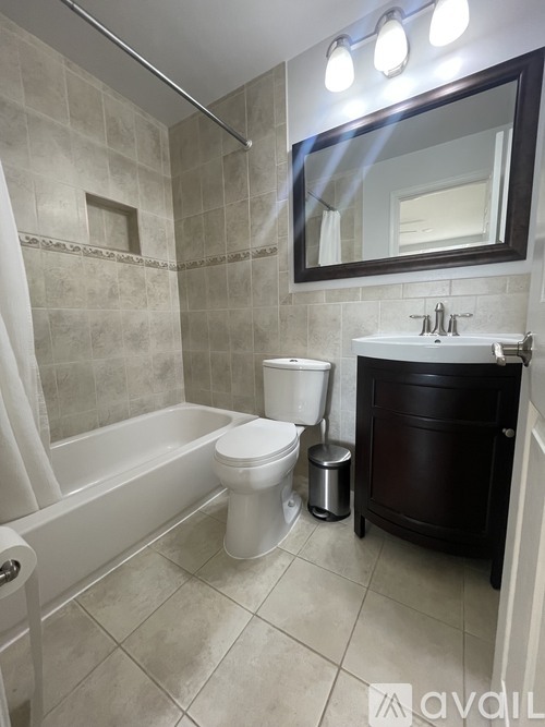 A bathroom with a toilet, a tub, and a mirror.