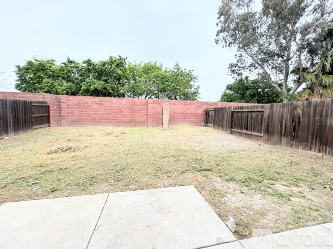 A backyard with a concrete slab and a wooden fence.