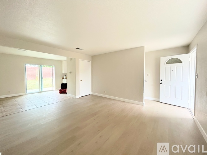 A spacious room with wooden flooring and white walls.
