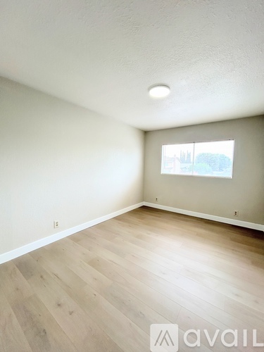 A room with wooden flooring and a window showing a view of a building.