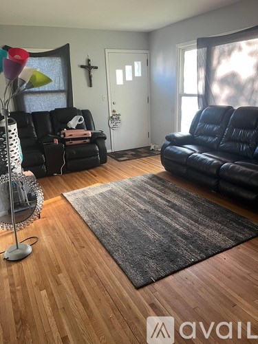 A living room with black leather sofas and a wooden floor.
