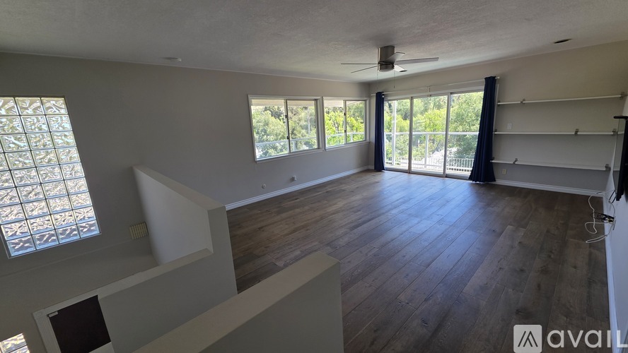 A spacious room with wooden floors and large windows.