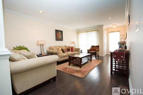 A living room with a beige couch, a wooden coffee table, and a painting on the wall.