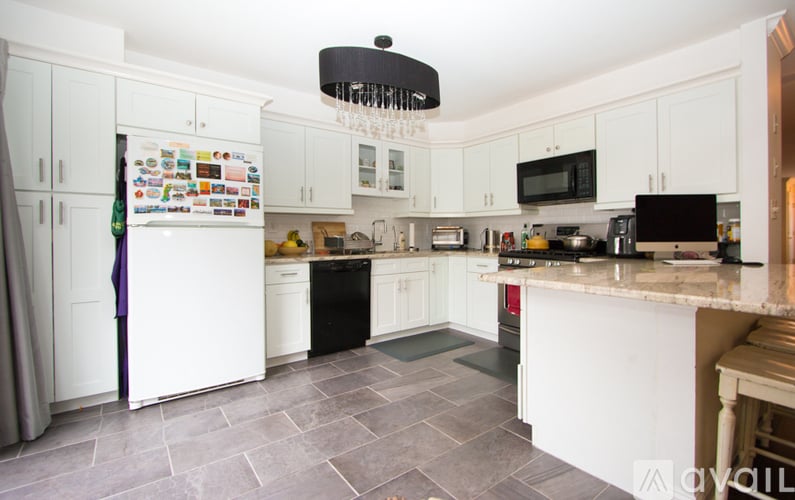 A kitchen with white cabinets and a black fridge.