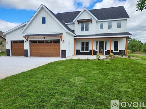 A white house with a black roof and a brown garage door.