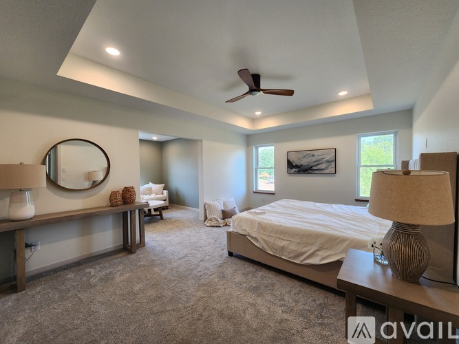 A bedroom with a bed, a bench, and a ceiling fan.