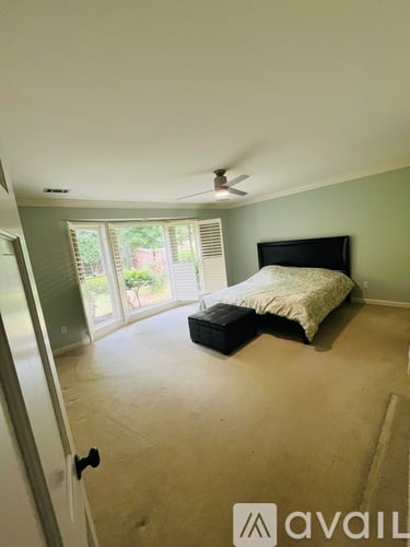 A bedroom with a bed, a ceiling fan, and a sliding glass door.