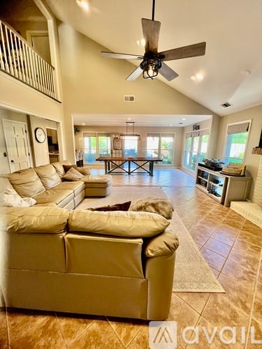 A spacious living room with a beige sofa and a ceiling fan.
