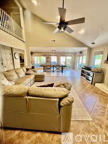 A spacious living room with a beige sofa and a ceiling fan.