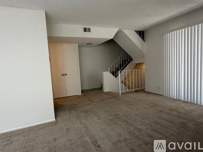 A spacious room with a staircase and a carpeted floor.