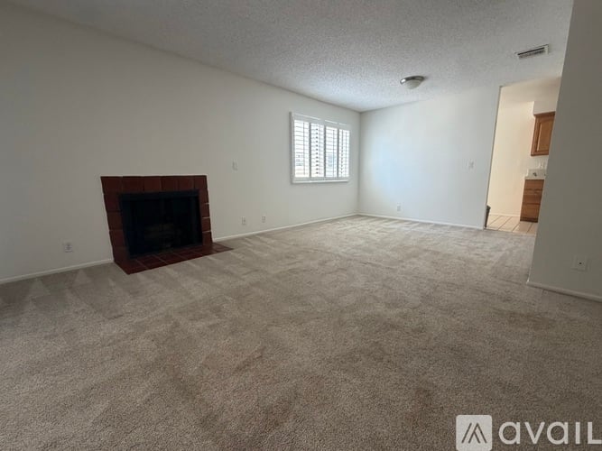 A spacious living room with a fireplace and carpeted floor.