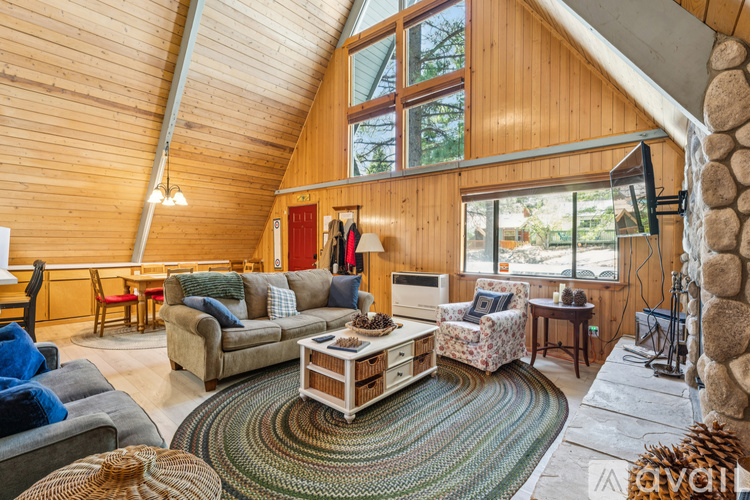 A living room with a stone fireplace and a large rug.