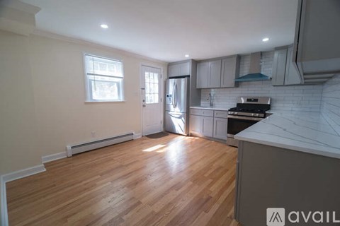 A kitchen with a white counter top and wooden floors.