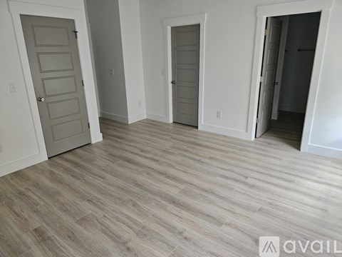 A room with a wooden floor and three doors.