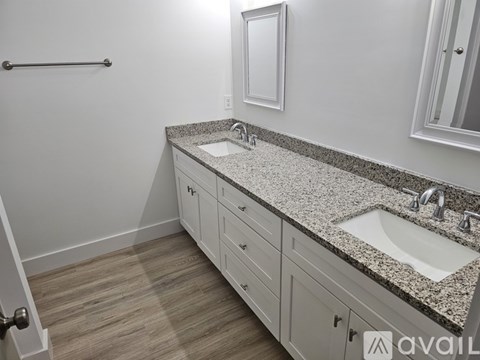 A bathroom with a granite countertop and white cabinets.