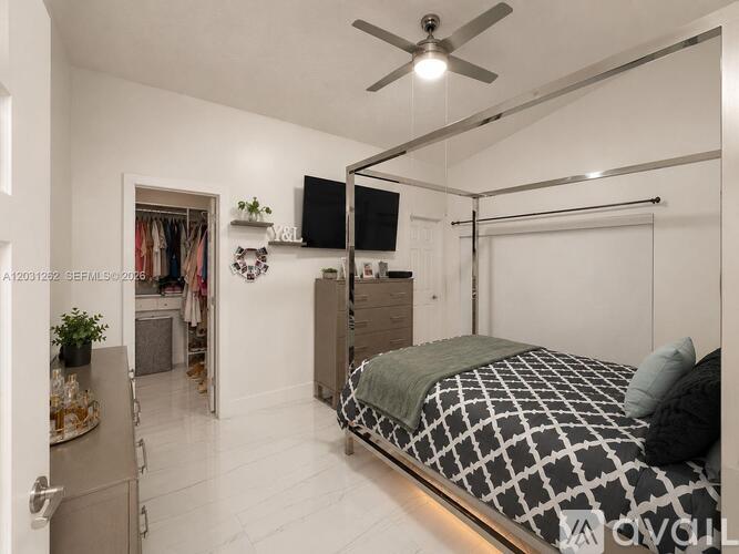 A bedroom with a bed, dresser, and a ceiling fan.