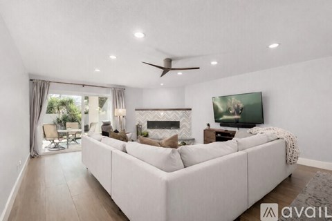 A living room with a white couch and a television on the wall.