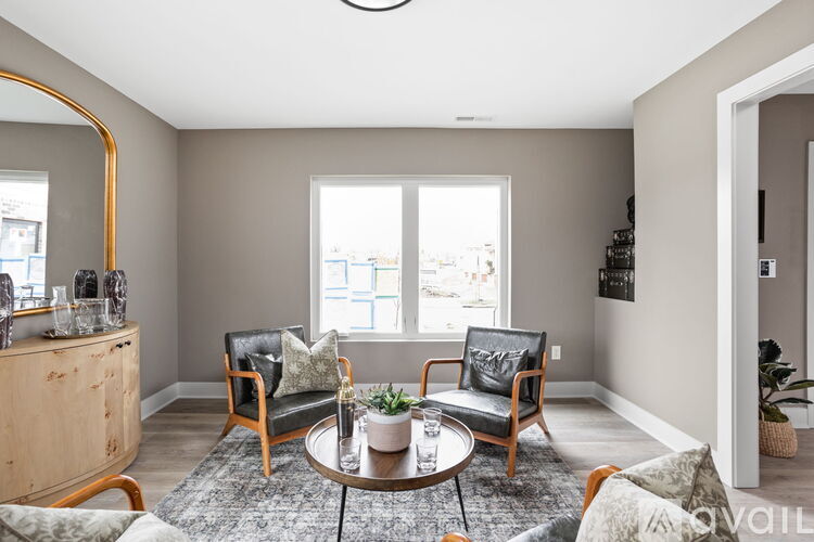 A living room with a round coffee table and two chairs.