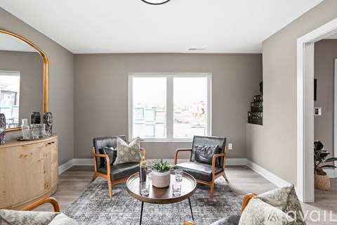 A living room with a round coffee table and two chairs.
