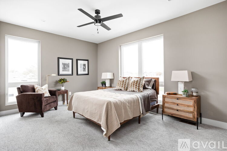 A bedroom with a bed, a chair, a nightstand, and a ceiling fan.