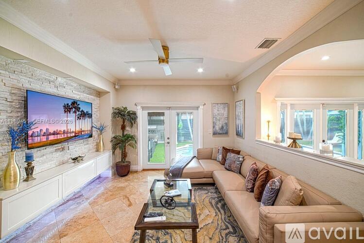 A living room with a couch, a coffee table, and a flat screen TV mounted on the wall.