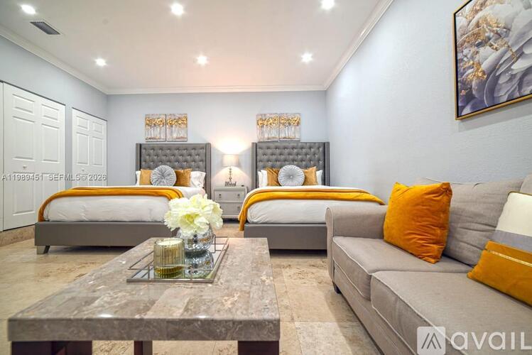A modern bedroom with two beds and a grey sofa.