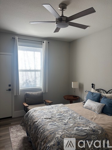 A bedroom with a bed, a fan, and a window with curtains.