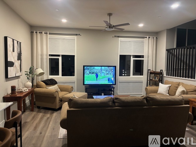 A living room with a brown couch and a television on the wall.