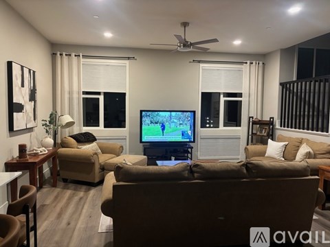 A living room with a brown couch and a television on the wall.