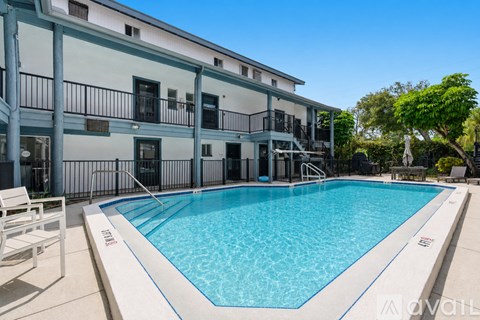 A swimming pool is located in front of a building with balconies.
