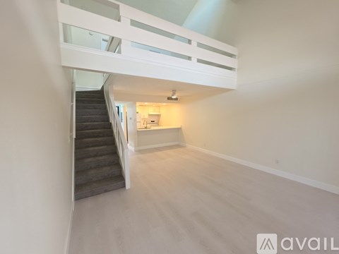 A spacious room with a staircase leading to the upper level.