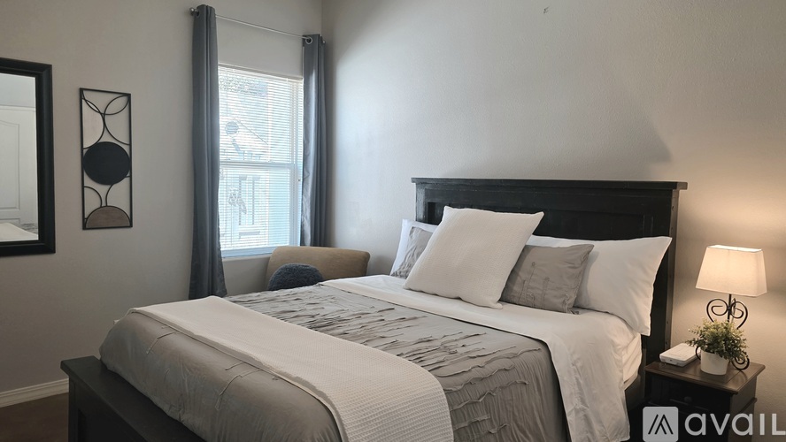 A well-lit bedroom with a large bed and a nightstand with a lamp.