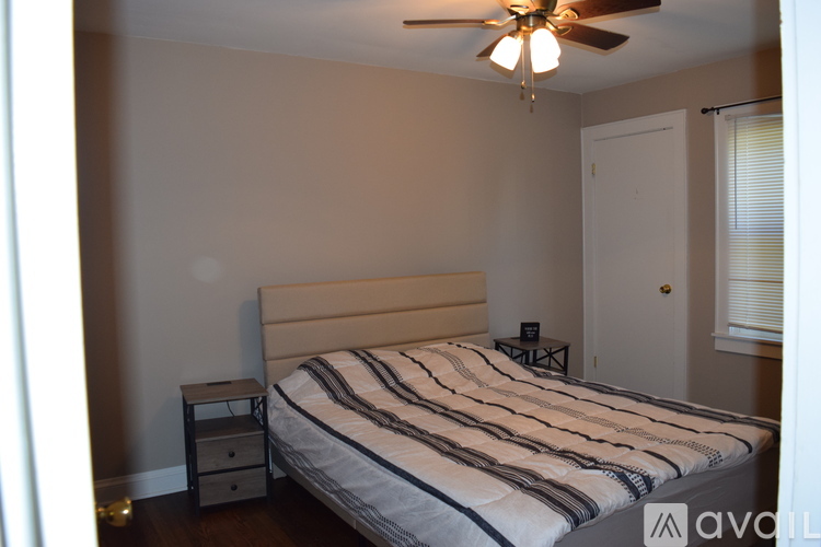 A bedroom with a bed, nightstand, and ceiling fan.