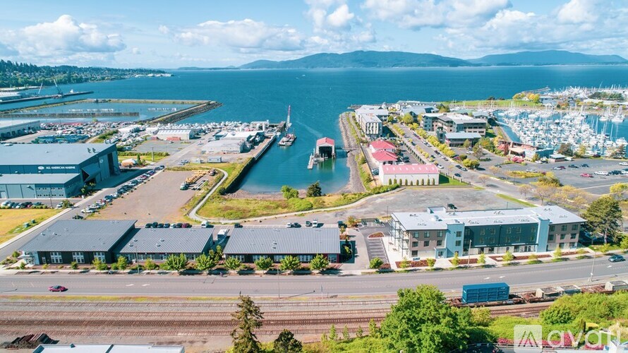 A large industrial area with a body of water and mountains in the background.