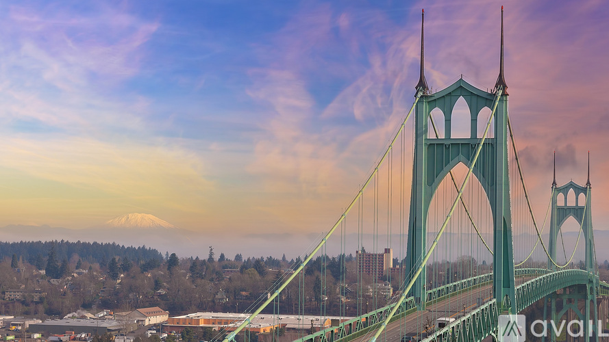 A bridge with a greenish hue spans across a river with a mountain in the background.