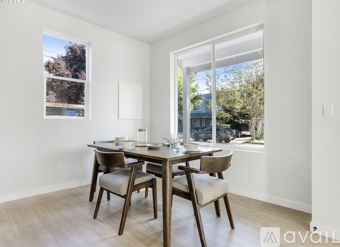 A dining room with a table set for four and a view of a backyard.