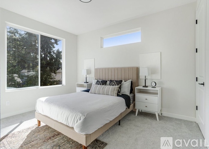 A bedroom with a large bed, a window with a view of trees, and a rug on the floor.