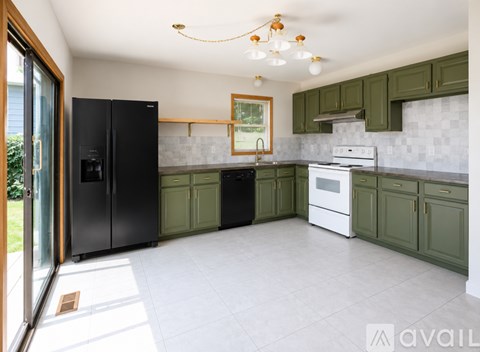 A kitchen with green cabinets and a black refrigerator.