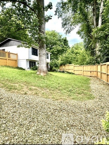 A white house with a brown fence and trees in the background.
