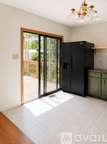 A kitchen with a black fridge and a wooden floor.