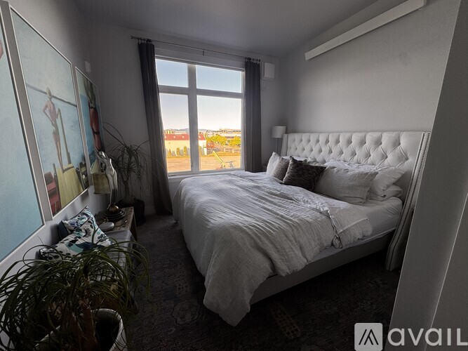 A bedroom with a large bed and a view of the outside through a window.