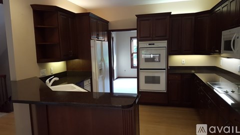 A kitchen with dark wood cabinets and a black countertop.