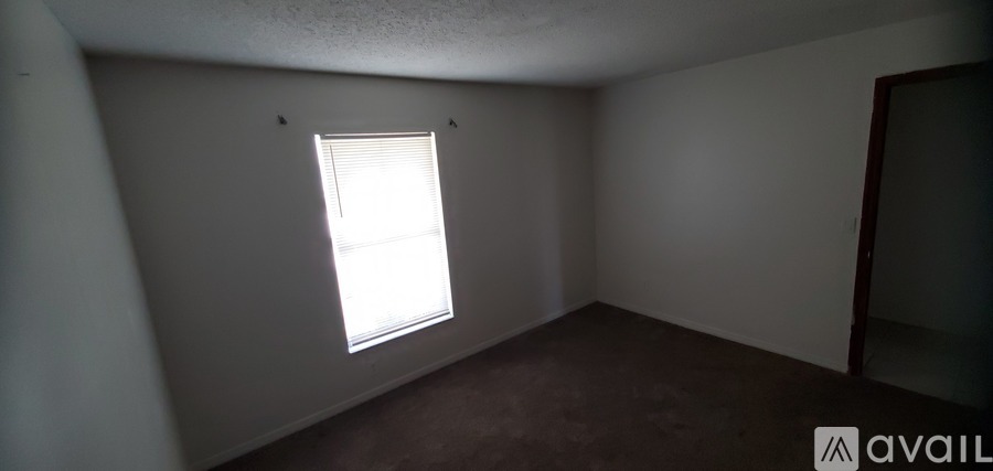 A room with a window and a carpeted floor.