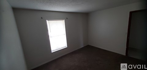 A room with a window and a carpeted floor.