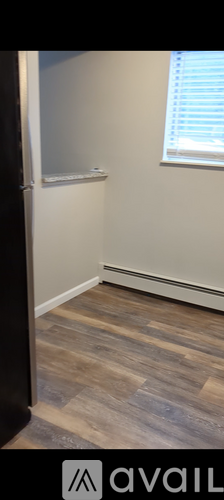 A room with a wooden floor and a window with blinds.