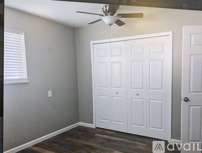 A room with a white door and a ceiling fan.