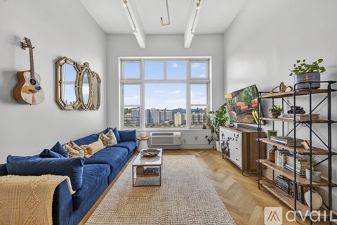 A living room with a blue couch and a guitar hanging on the wall.